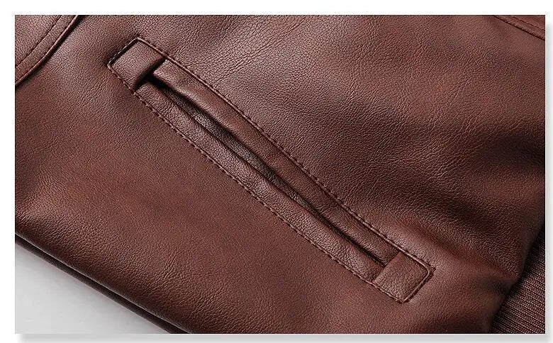 O close-up de uma Jaqueta de Couro Masculina com Capuz da Zellum mostra a fenda horizontal do bolso com costura precisa e couro liso e texturizado, enfatizando o brilho suave da jaqueta e o acabamento de alta qualidade.