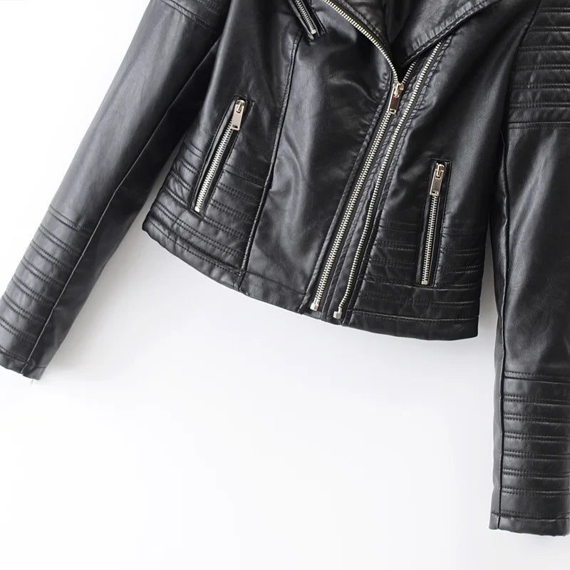 A Jaqueta de Couro Feminina Vogue Noir da Zellum, em PU preto, possui zíperes prateados, dois bolsos verticais com zíper e fechamento frontal assimétrico. Detalhes acolchoados nas mangas e cintura. Foto em fundo branco.