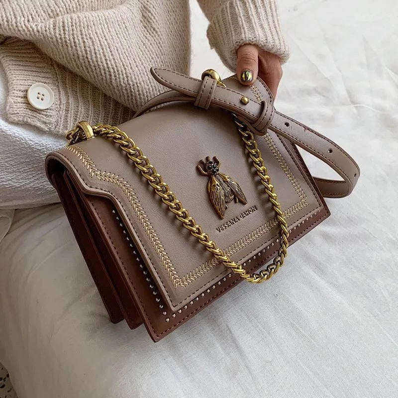 Alt text: Bolsa tiracolo feminina de couro estruturada preta elegante.