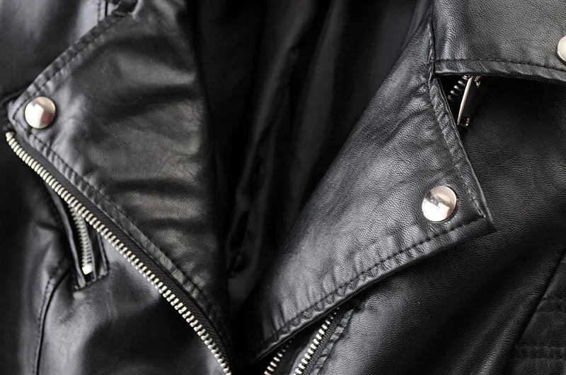Close-up da Jaqueta de Couro Feminina Vogue Noir da Zellum, com fechos prateados brilhantes, zíperes e couro PU texturizado. A jaqueta está parcialmente aberta, mostrando o forro liso e o estilo clássico de motociclista.