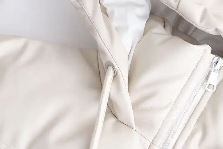 Close-up da Zellum Jaqueta Puffer Feminina para Inverno na cor creme, com capuz, cordão branco com ilhós prateado e zíper branco parcialmente fechado. O tecido macio e levemente acolchoado garante conforto extra para o inverno.