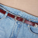 Cinto de couro bordô com fivela prateada em detalhe western na cintura de calça jeans