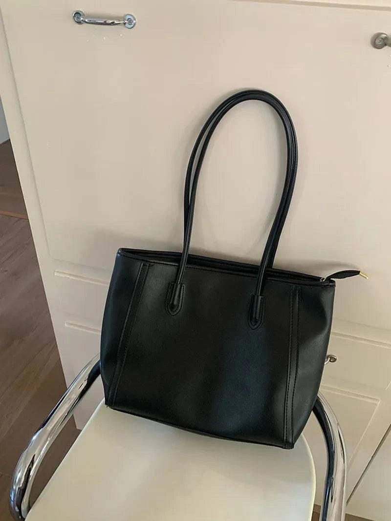 Alt text: Bolsa feminina de couro preto estilo tote elegante.