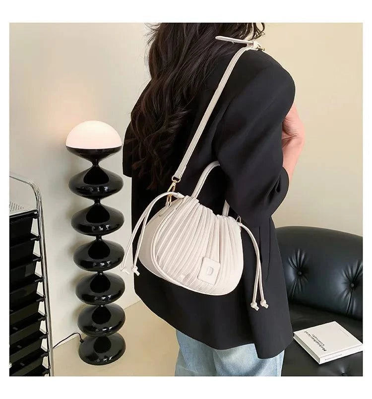 Alt text: Bolsa feminina bucket texturizada em tom neutro elegante.