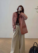 Mulher usando jaqueta de couro rosa vintage com calça bege clara e bolsa preta