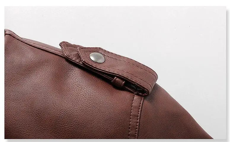 Close-up da Jaqueta de Couro Masculina com Capuz Zellum em couro marrom, com alça de ombro com botão de pressão prateado e costura visível. O couro liso e sutilmente granulado é mostrado contra um fundo branco liso.