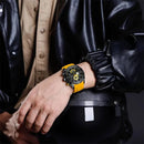 Relógio esportivo com mostrador preto e bezel amarelo em pulseira de silicone, usado no pulso