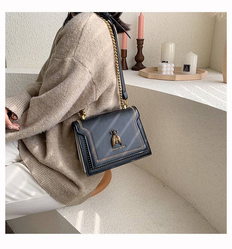 Alt text: Bolsa tiracolo feminina de couro estruturada preta elegante.