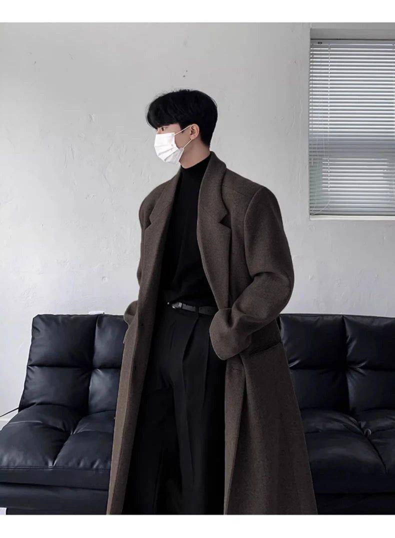 Sobretudo Coreano Masculino Longo marrom usado com suéter preto e calça social. Estilo clássico e elegante para dias frios com toque coreano.