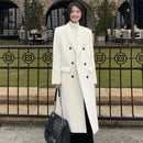 Mulher vestindo sobretudo longo off-white com abotoamento duplo e bolsa preta