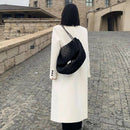 Mulher de costas usando sobretudo longo off-white com bolsa preta acolchoada