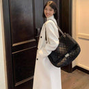 Mulher com sobretudo longo off-white e bolsa preta acolchoada