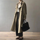 Trench coat longo bege em corte clássico com lapela aberta, calça preta e bolsa preta