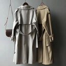Dois trench coats femininos em tons neutros, vista traseira, com cintos e detalhes nos ombros