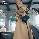 Mulher usando trench coat bege com cinto e bolsa transversal acolchoada azul-marinho