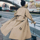 Mulher de costas usando trench coat bege com cinto e bolsa preta