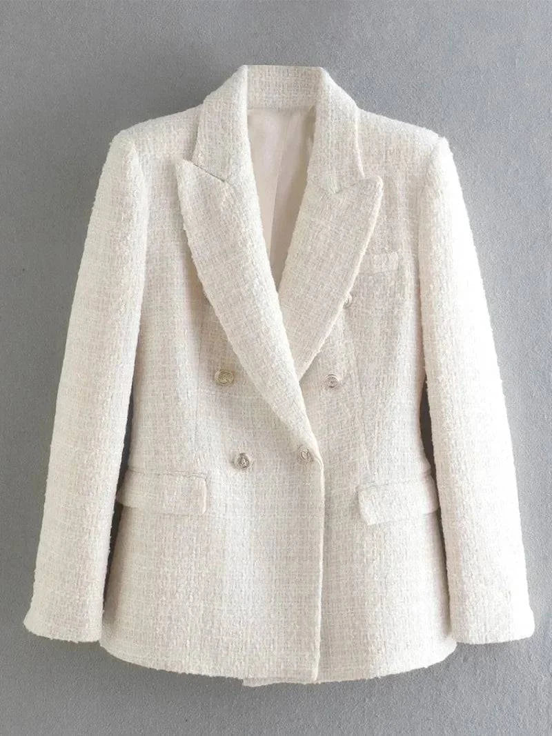 Blazer alfaiataria feminino branco texturizado pendurado contra parede cinza