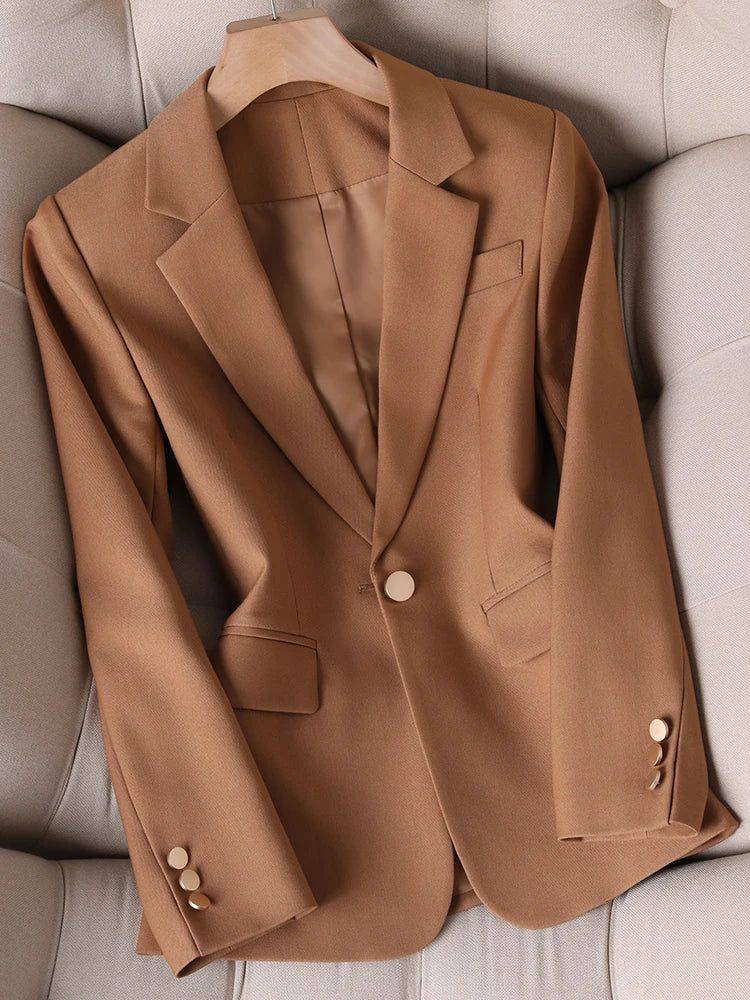 Blazer feminino alfaiataria caramelo com botão único, exposto em cabide