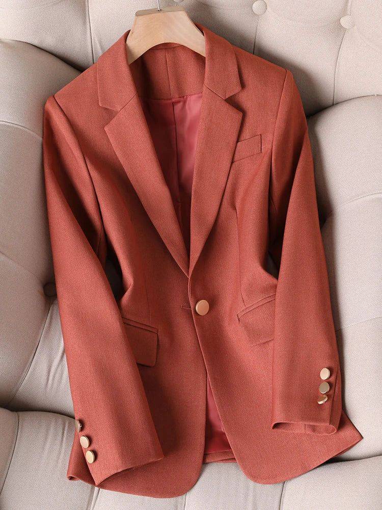 Blazer feminino alfaiataria terracota com forro rosado, exibido em sofá estofado