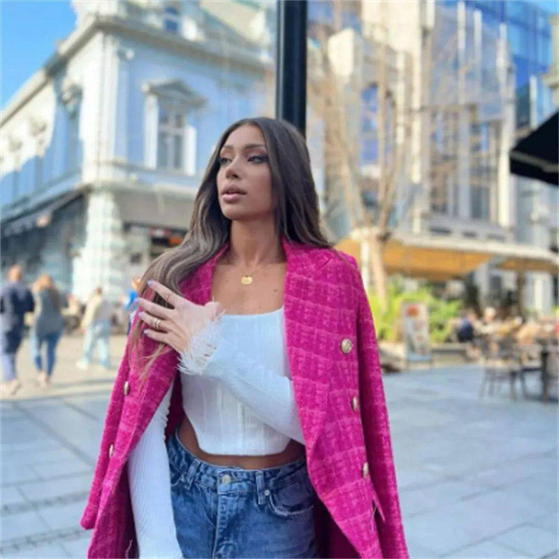 Mulher com blazer rosa xadrez nos ombros, ideal para um look moderno e ousado.