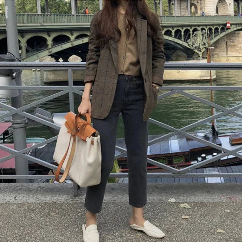 Look casual com blazer feminino marrom e bolsa clara em cenário urbano