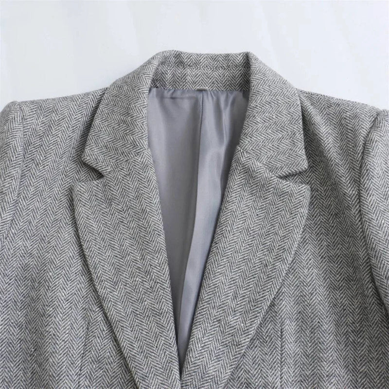 Close do colarinho do Blazer Social Feminino Cinza, com lapela clássica em tecido elegante com padrão espinha de peixe.