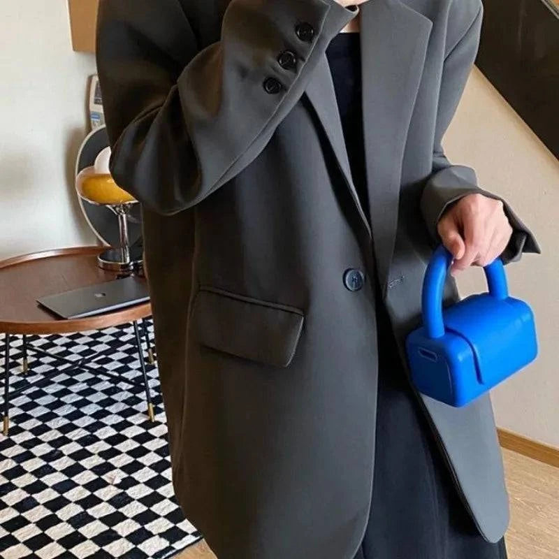 Blazer feminino liso na cor cinza, estilo social, combinado com bolsa azul moderna