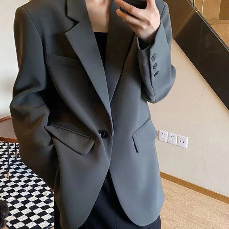 Blazer social feminino cinza liso com caimento elegante e corte reto sobreposto a blazer preto