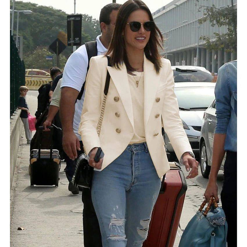 Modelo usando blazer Majesko bege com botões dourados, combinando com calça jeans rasgada e óculos escuros
