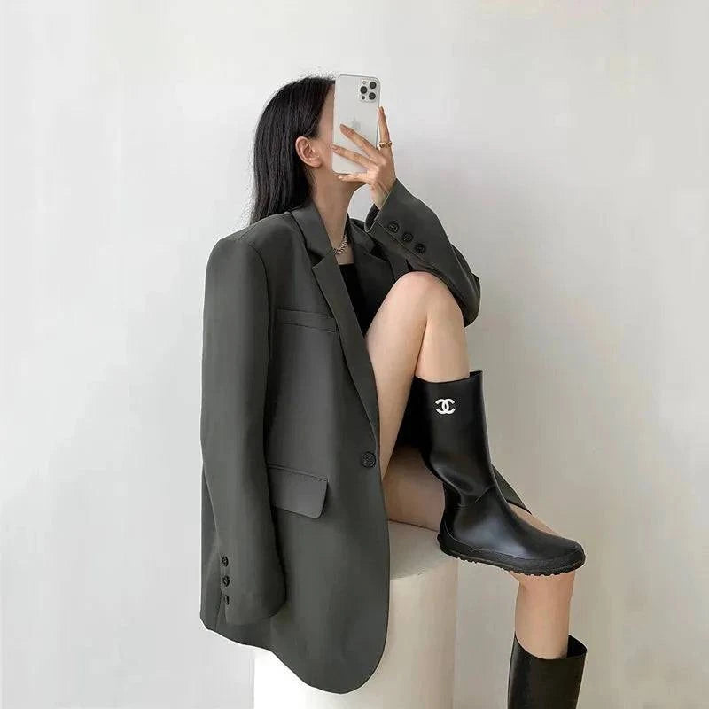 Blazer social feminino oversized cinza escuro com bota preta e fundo branco