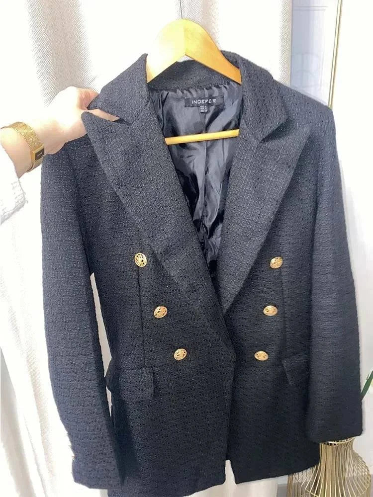 Blazer social feminino preto com botões dourados pendurado em cabide de madeira