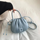 Bolsa bucket azul-claro com textura franzida, alça de mão e transversal