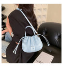 Bolsa bucket azul-claro texturizada com fecho de cordão e alça ajustável