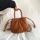 Bolsa bucket feminina texturizada caramelo com pregas verticais, alças duplas e fecho com cordão