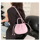 Bolsa bucket rosa com textura plissada, alças brancas e placa quadrada, sobre modelo