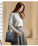 Mulher com bolsa preta de couro com alças duplas ajustáveis, estilo crossbody