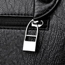 Detalhe do zíper prateado de bolsa crossbody em couro texturizado preto
