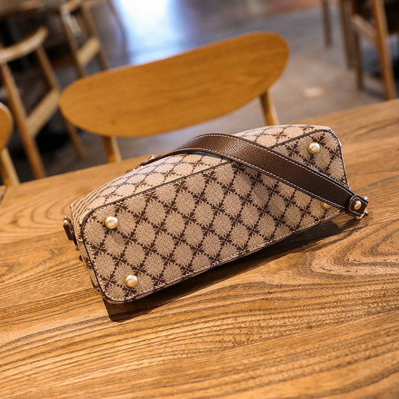 Bolsa Feminina de Couro Elite bege. Detalhe da base com estampa de monograma e pés de metal dourados. Acabamento de alta qualidade.