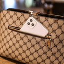 Bolsa bege com estampa de monograma e compartimento com zíper contendo celular branco