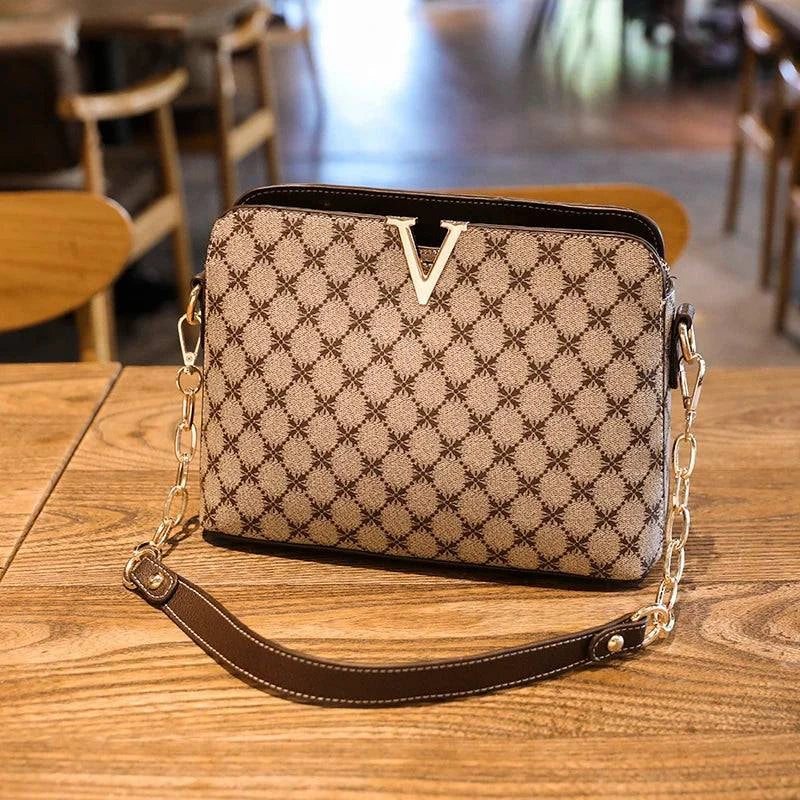 Bolsa Feminina de Couro Elite bege, estampa de monograma, logo "V" dourado. Alça de corrente e detalhes em couro marrom. Sofisticada e elegante.