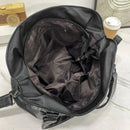 Bolsa de couro preta aberta mostrando o interior espaçoso com forro escuro
