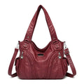 Bolsa feminina de couro legítimo Charmonia na cor vinho, com alças de ombro largas, detalhes trançados na frente, bolsos laterais e ferragens prateadas.