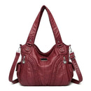 Bolsa feminina de couro legítimo Charmonia na cor vinho, com alças de ombro largas, detalhes trançados na frente, bolsos laterais e ferragens prateadas.