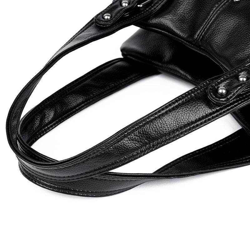 Bolsa Feminina Couro Legítimo Luxe Essence preta. Detalhe das alças de mão em couro texturizado com rebites prateados. Conforto e estilo.