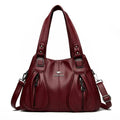 Bolsa Feminina Couro Legítimo Luxe Essence vinho, com bolsos frontais e ferragens prateadas. Alças duplas e transversal. Elegante e funcional.