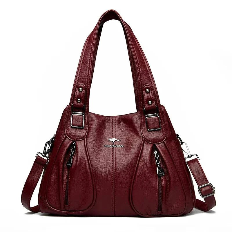 Bolsa Feminina Couro Legítimo Luxe Essence vinho, com bolsos frontais e ferragens prateadas. Alças duplas e transversal. Elegante e funcional.