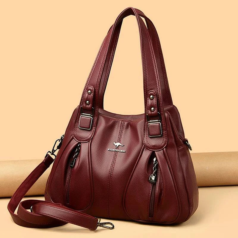 Bolsa Feminina Couro Legítimo Luxe Essence vinho, com bolsos frontais e ferragens prateadas. Alças duplas e transversal. Elegante e funcional.