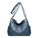Bolsa feminina de couro Loox azul acinzentado com alça transversal e múltiplos bolsos frontais com zíper, destacando o design em painéis e a costura.