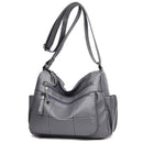 Bolsa feminina de couro cinza com alça transversal e bolsos com zíper