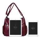 Bolsa feminina vinho com alça transversal ao lado de iPad Air e iPad Mini para referência de tamanho